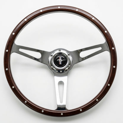 A classic Ford steering wheel featuring a dark brown wood-grain rim with silver rivets and polished chrome three-spoke metal arms, centered with a chrome hubcap displaying the black and silver Ford pony logo.