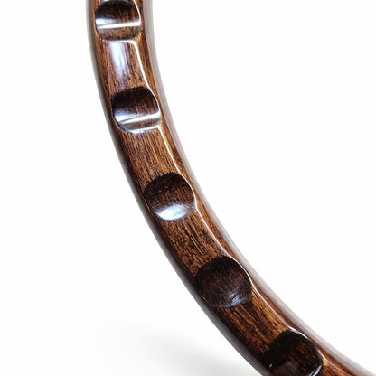 A close-up of a curved, glossy dark brown wooden object with four evenly spaced oval cutouts, shown against a plain white background.