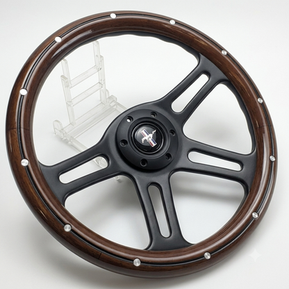 A four-spoke steering wheel with a dark brown wood-grain outer rim and a matte black center, accented with silver rivets, displayed on a white background with a clear plastic stand.