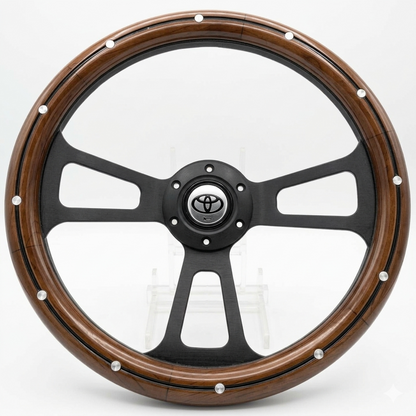 A custom car steering wheel featuring a glossy black five-spoke center with a silver Toyota emblem, surrounded by a thick brown wood-grain outer rim accented with silver rivets.