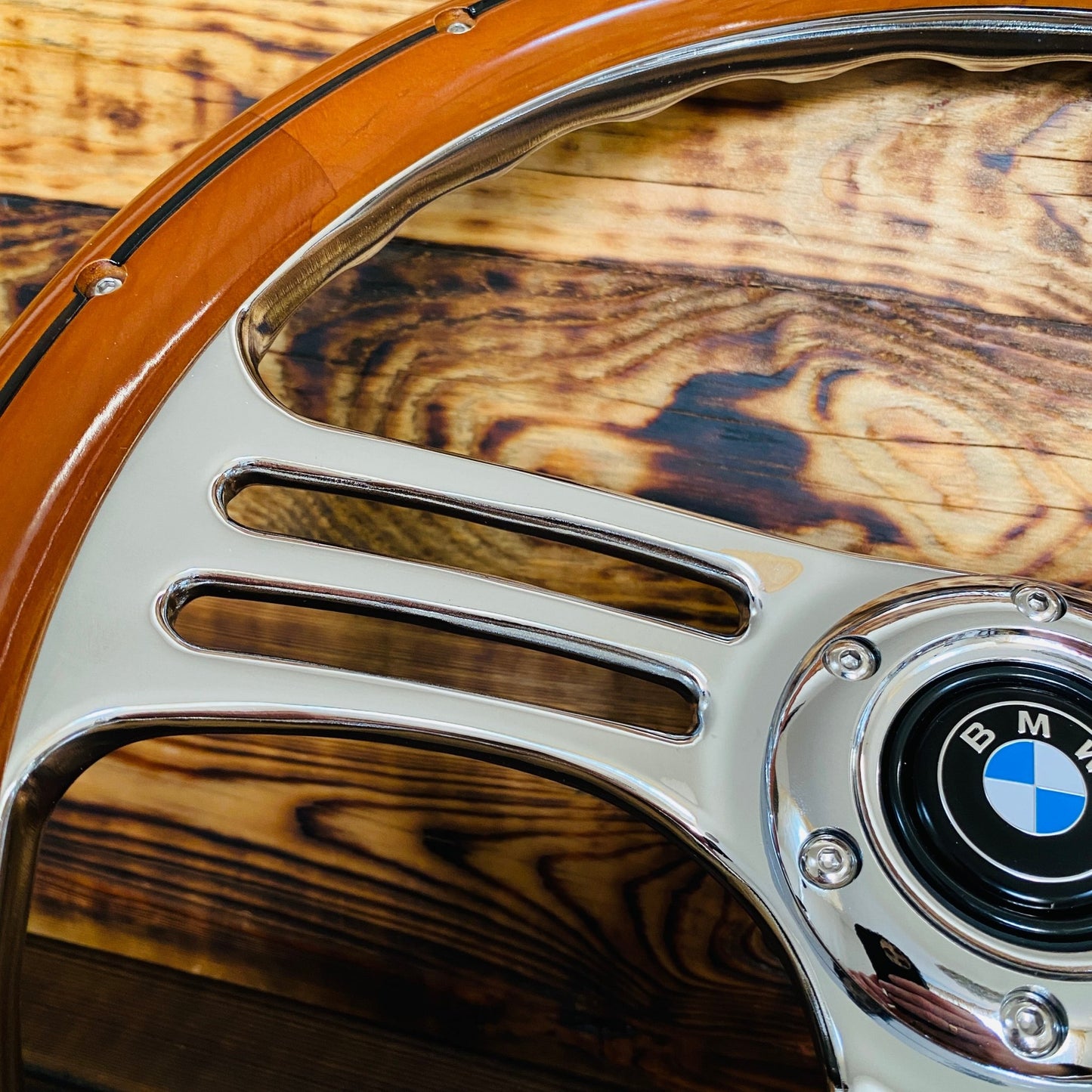 14-inch wood and chrome BMW steering wheel showing polished spokes and center emblem close-up