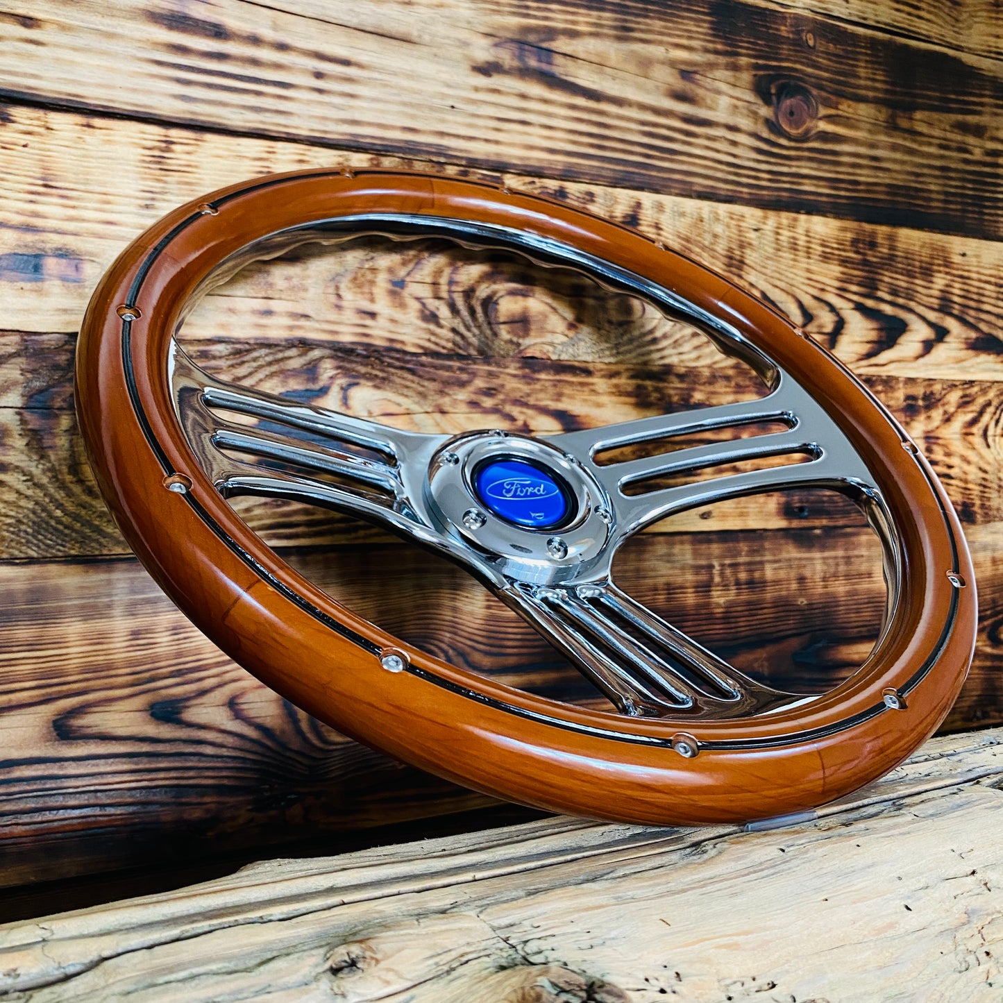 14in Ford wood steering wheel with polished metal spokes and blue center cap, angled view