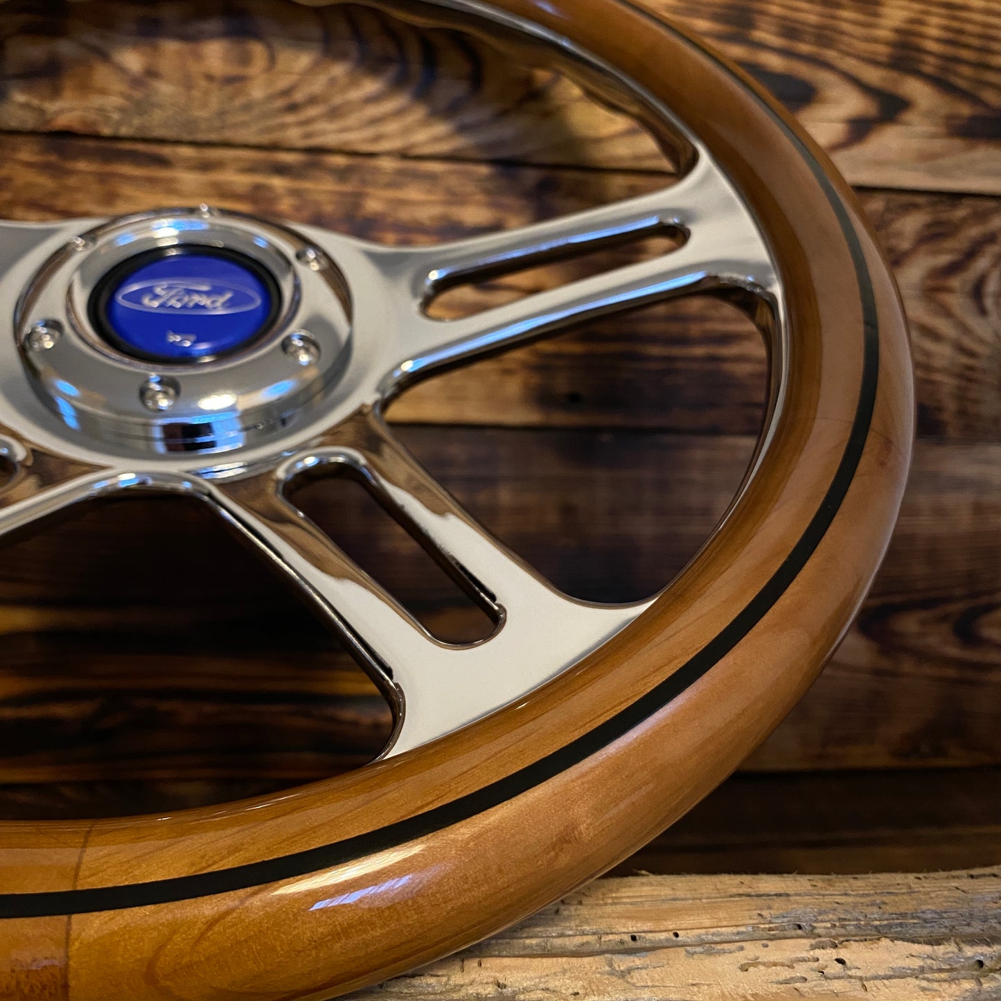 14 inch wood steering wheel for Ford with polished metal spokes and center emblem close-up view