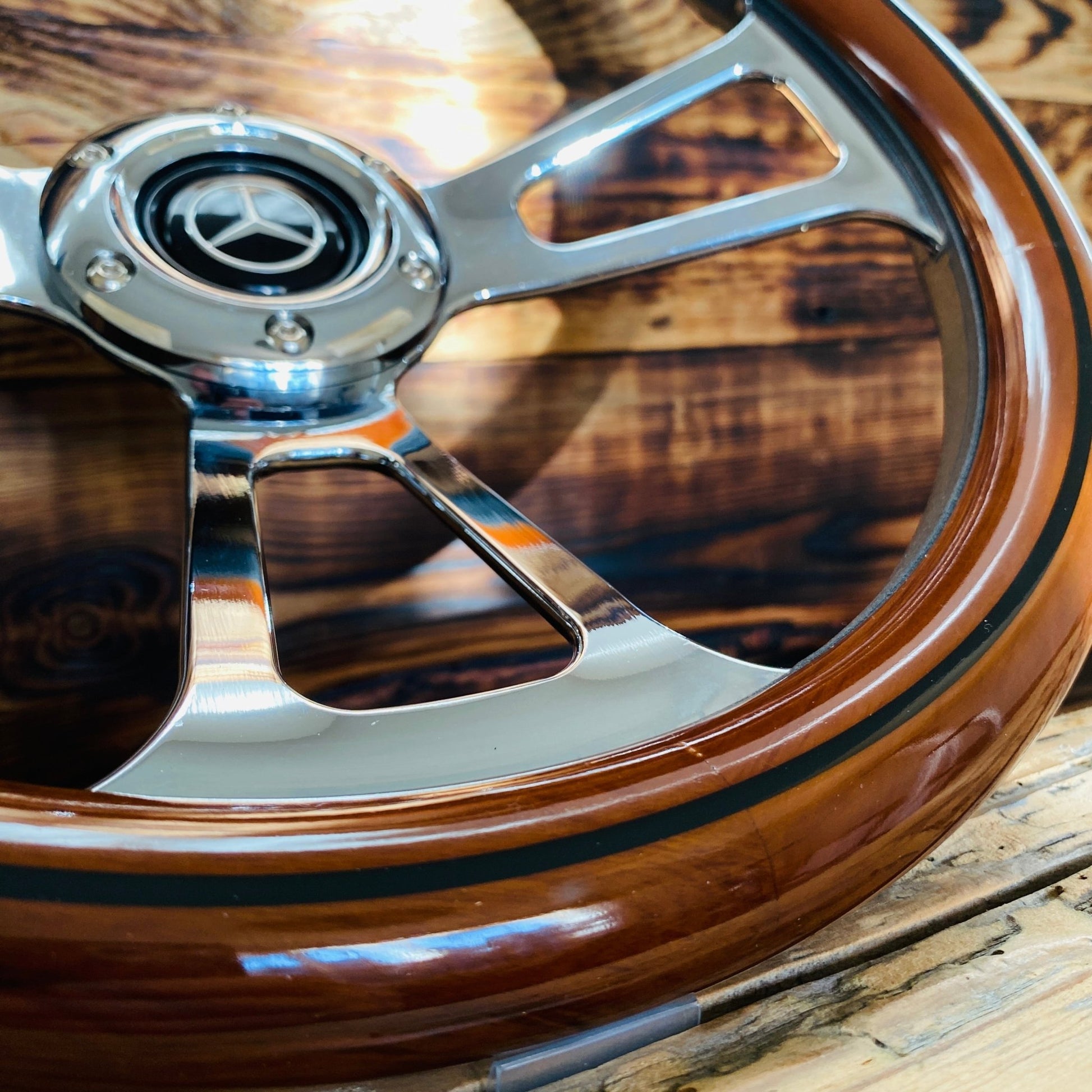 14 inch Mercedes wood steering wheel with polished metal spokes and center emblem close-up view