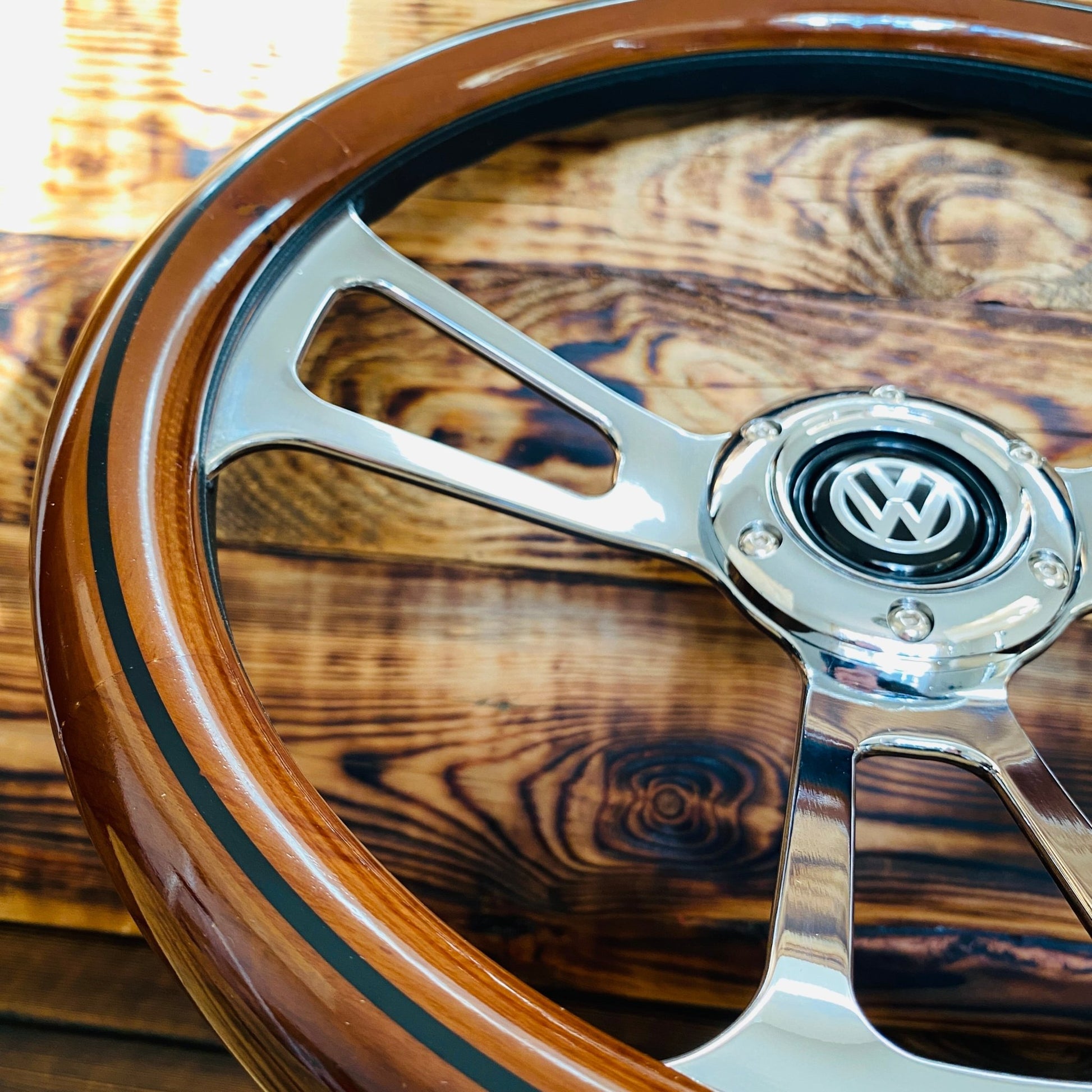 14 inch wood steering wheel for VW with polished metal spokes and VW emblem close-up view