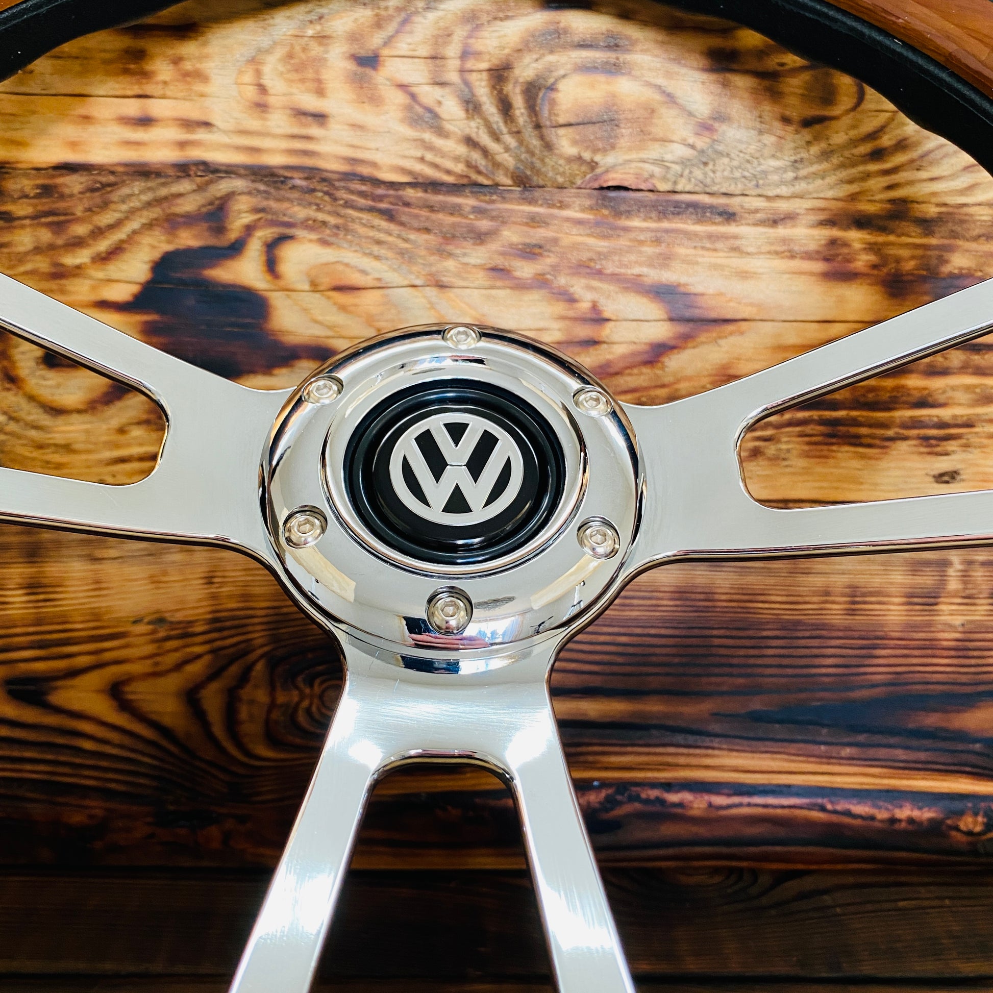 14 inch wood steering wheel for VW with polished metal spokes and VW emblem center close-up view